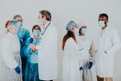 Portrait of doctors wearing mask standing against white background
