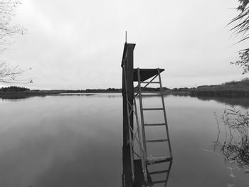 View of wooden posts in lake against sky