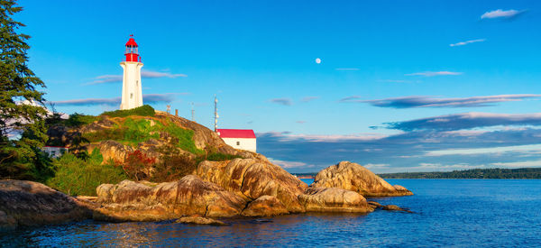 Lighthouse by sea against sky