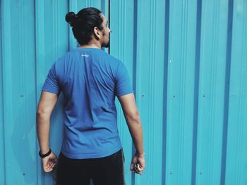 Mid adult man standing against blue wall