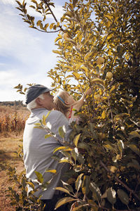 Grandfather assisting granddaughter for picking apple in orchard