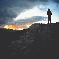 Silhouette of man standing on landscape at sunset