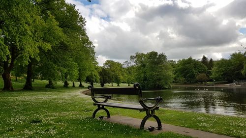 Empty bench in park against sky