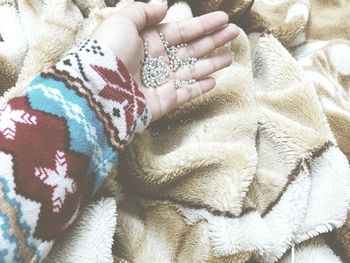 Cropped hand holding beads on blanket