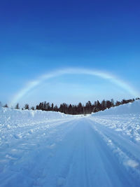 Snow covered landscape against blue sky