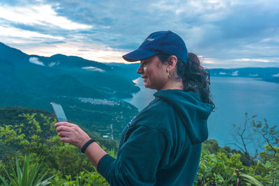 Side view of man using mobile phone against sky