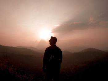 Silhouette man standing on mountain against sky during sunset