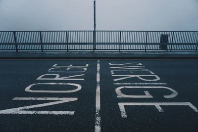 Road marking on bridge by railing during foggy weather