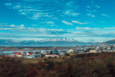 High angle view of houses and mountains against blue sky