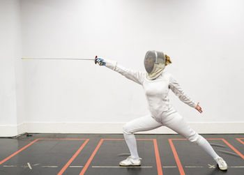 Woman in fencing outfit practicing at gym