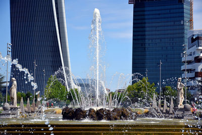 Fountain in city against sky