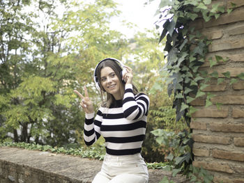 Portrait of young woman standing against wall