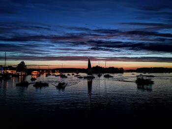 Silhouette boats in sea at sunset