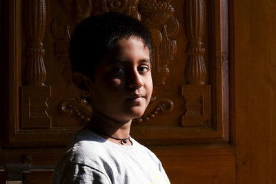 Portrait of smiling boy standing by door at home