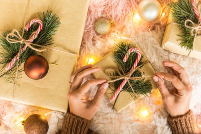 Cropped hands of woman with christmas decorations on table