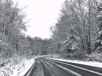 Road amidst trees against sky during winter