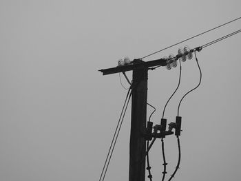 Low angle view of bird perching on electricity pylon against clear sky