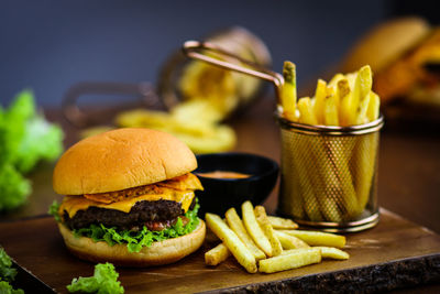 Close-up of burger with french fries served on wooden table