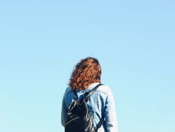 Rear view of woman standing against clear blue sky