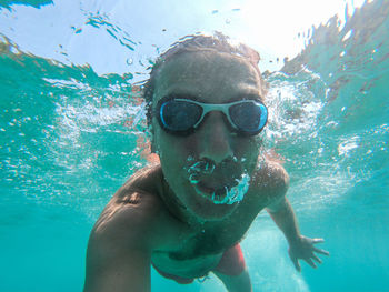 Funny guy having fun and taking underwater selfie while swimming in the sea