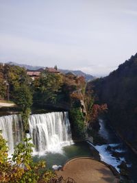 Scenic view of waterfall against sky