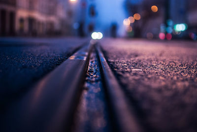 Close-up of railroad track on street in city at night