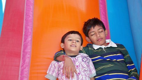 Brothers leaning on colorful inflatable outdoor play equipment