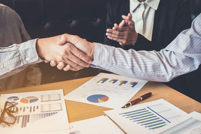 Close-up of business shaking hands while working in office