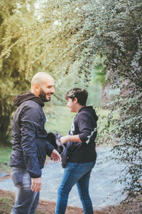 Side view of father and son standing in park