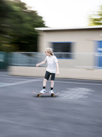 Blurred motion of boy skateboarding on road