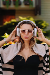 Portrait of young woman wearing sunglasses standing outdoors