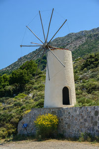 Traditional windmill on mountain against sky