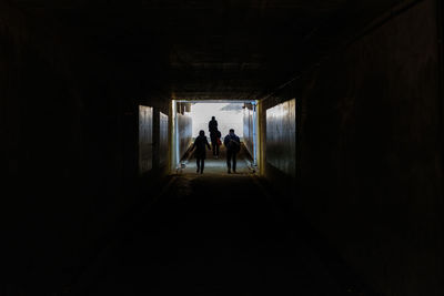 Rear view of silhouette people walking in tunnel