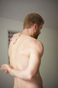 Rear view of shirtless man exercising at home