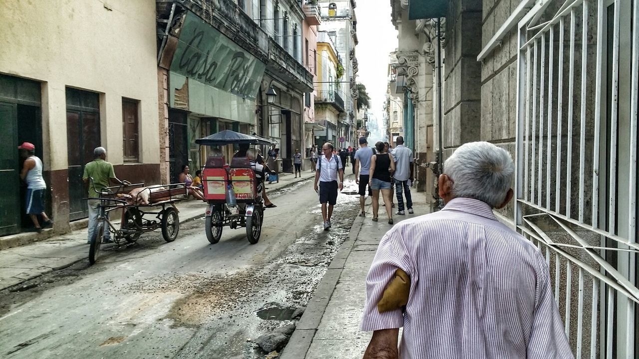 building exterior, architecture, built structure, men, city, street, lifestyles, person, city life, walking, transportation, rear view, leisure activity, building, mode of transport, full length, city street, residential structure, casual clothing