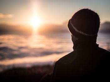 Rear view of silhouette man standing against sea during sunset