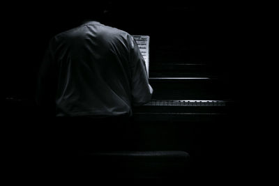 Rear view of man playing piano