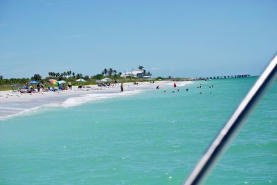 People on beach against clear blue sky