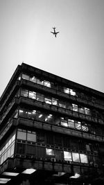 Low angle view of airplane flying in building against sky