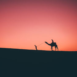 Silhouette man riding horse against clear sky