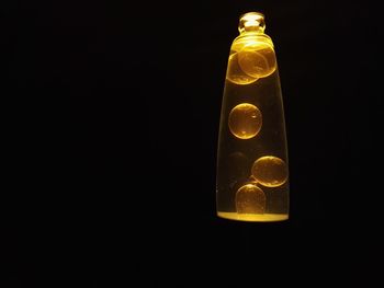 Close-up of illuminated light bulb over black background