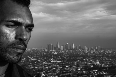 Portrait of man looking at city buildings against sky