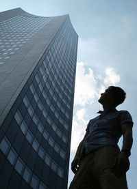 Man looking at modern skyscraper against sky