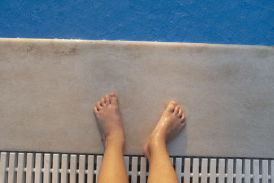 Low section of woman standing by swimming pool