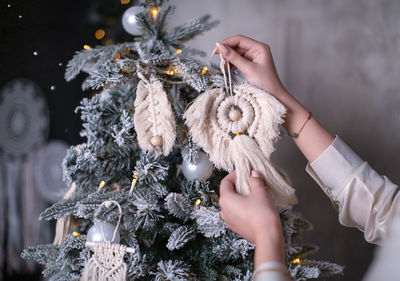 Midsection of woman hanging ornament on christmas tree