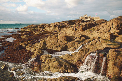 Water flowing through rocks against sky