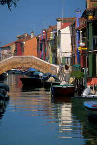 Boats moored in canal by buildings in city