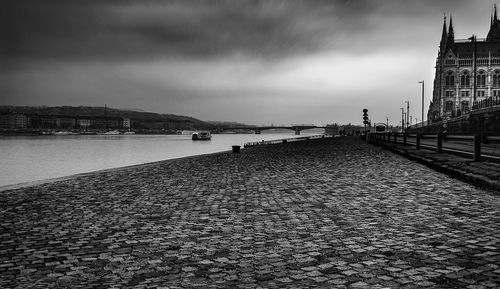 Buildings by river against cloudy sky