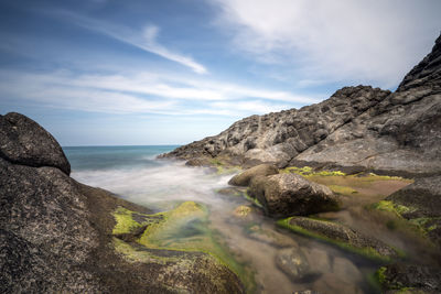 Scenic view of sea by mountain against sky