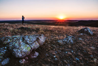 Low angle view of silhouette man standing on field at sunset